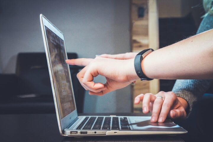 Two people pointing at a laptop discussing the effectiveness of bottom-of-the-funnel marketing strategies.