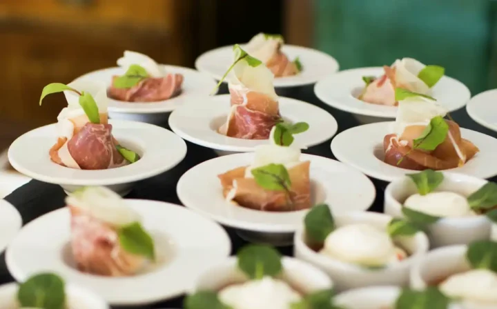 bite sized prosciutto appetizers with cheese and microgreens on plates